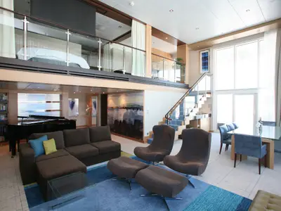 Helle und geräumige zweistöckige Loft-Suite mit großem Fenster, Sofa, Esstisch, Piano und Schlafbereich im Obergeschoss.