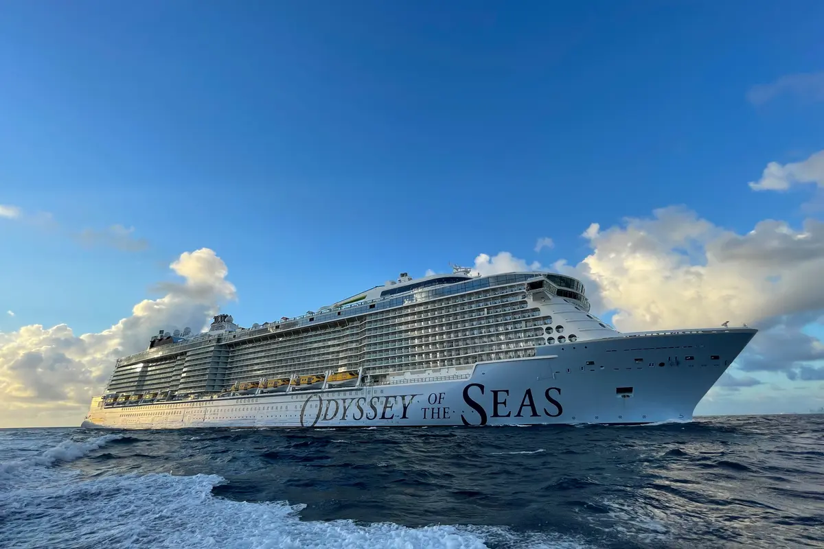 Große Odyssey of the Seas auf blauem Meer unter strahlendem Himmel. Weißer Rumpf mit dunklem Schriftzug und vielen Balkonkabinen.