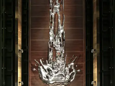 Wandkunst an Bord der Odyssey of the Seas: Eine glänzende, silberne Skulptur, die flüssiges Metall darstellt, auf dunklem Holzpaneel, flankiert von strukturierten Säulen.