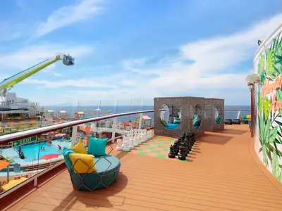 Das Sonnendeck der Odyssey of the Seas mit Poolbereich, großem Schachspiel, Lounge-Inseln und der North Star Gondel unter blauem Himmel über dem Meer.