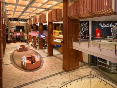 Das helle, mehrstöckige Atrium der Quantum of the Seas. Zu sehen sind Geschäfte, Restaurants und eine 'Wonderland'-Dekoration.