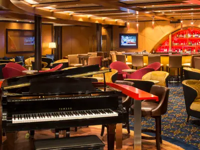 Elegante Lounge mit Yamaha-Flügel und Bar auf der Quantum of the Seas. Komfortable Sessel und eine rot beleuchtete Flaschenwand prägen den Raum.