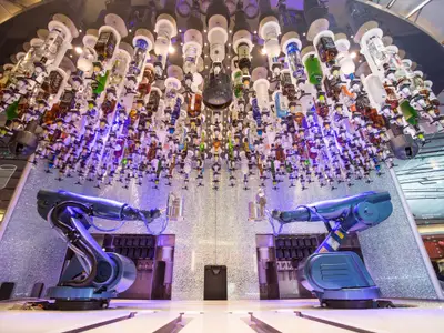 An der Bionic Bar der Quantum of the Seas mixen zwei Roboterarme Getränke. Hunderte von Spirituosenflaschen hängen umgedreht und beleuchtet von der Decke.