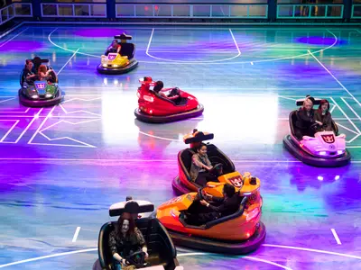 Gäste fahren in bunten Bumper Cars auf dem Seaplex der Quantum of the Seas. Der beleuchtete Sportboden zeigt lila, blaue und grüne Reflektionen und Linien.