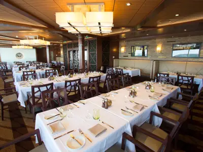Innenaufnahme eines Restaurants der Quantum of the Seas. Gedeckte Tische, Holzstühle und Bänke, Holzwände und Decken mit modernen Leuchten.