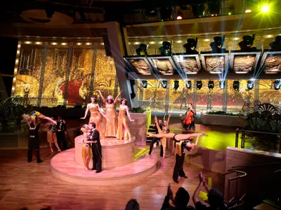 Bühnenshow im Two70° der Quantum of the Seas mit Akrobaten, Tänzern und Sängern. Eine große Videowand zeigt eine goldene Art-déco-Kulisse.