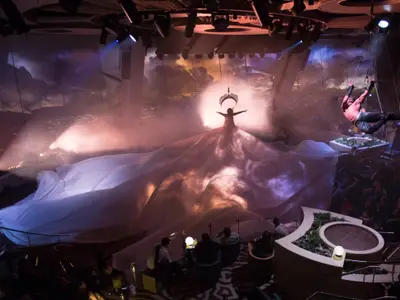 Bühnenshow auf der Quantum of the Seas: Artistin in großem Tuch, Akrobat an Seilen. Licht, Nebel und Himmels-Projektion umgeben das Publikum.
