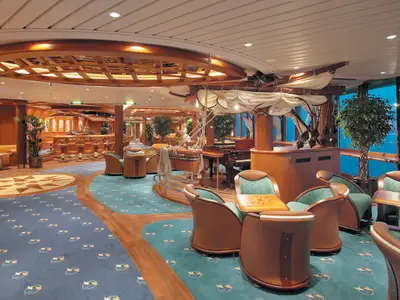 Innenansicht der Schooner Bar auf der Serenade of the Seas, mit Holzvertäfelung, maritimen Details, einer Bar, bequemen Sitzbereichen, einem Klavier und großen Fenstern zum Meer hin.