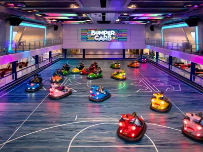 Bumper-Car-Arena der Spectrum of the Seas zeigt Gäste in bunten Fahrzeugen auf dem beleuchteten Parcours. LED-Anzeige im Hintergrund.