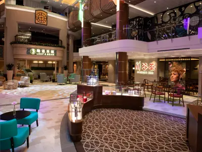 Das weitläufige Innenatrium der Spectrum of the Seas zeigt Geschäfte wie Leaf & Bean und das Sichuan Red Restaurant. Verschiedene Sitzbereiche und ein Verkaufsstand prägen die Szene auf mehreren Ebenen.