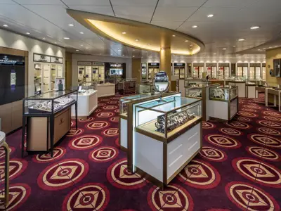 Ein elegantes Uhrengeschäft an Bord der Spectrum of the Seas zeigt Luxusuhren in beleuchteten Vitrinen. Auffälliger, gemusterter Teppichboden.