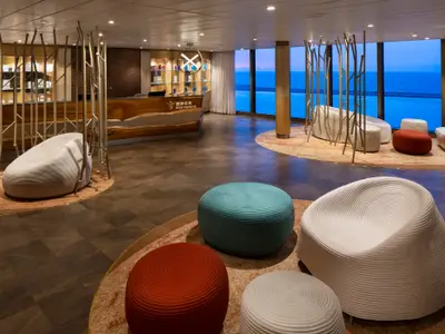 Rezeptionsbereich auf der Spectrum of the Seas mit Blick auf das Meer. Moderne Sitzgelegenheiten und Holzdekor schmücken den Raum.