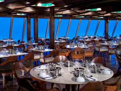 Modernes Restaurant der Spectrum of the Seas: Zahlreiche Tische mit Geschirr sind gedeckt. Große Fenster bieten einen weiten blauen Meerblick.