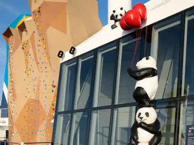 Auf der Spectrum of the Seas: Kletterwand und Panda-Statuen. Ein Panda auf einem anderen greift nach roten Ballons, gehalten von einem dritten oben.