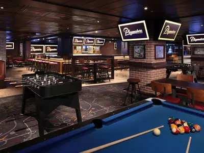 Die Sportsbar Playmakers auf der Star of the Seas zeigt einen Billardtisch im Vordergrund, einen Kickertisch und eine Bar. Backsteinwände, Sportmotive auf dem Teppich und helle Schilder prägen den Raum.