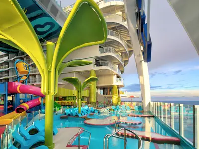 Star of the Seas: Lebhafter Kinderwasserpark an Deck mit bunten Rutschen, Pools und Wasserspielen. Balkone und Meer im Hintergrund sind zu sehen.