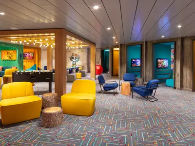 Innenansicht eines farbenfrohen Freizeitbereichs auf der Star of the Seas mit Gaming-Stationen, einem Kicker und verschiedenen Sitzgelegenheiten.