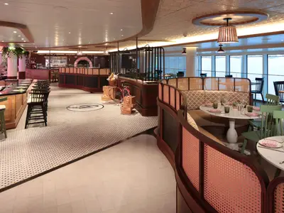 Gastronomiebereich auf der Star of the Seas: Bar, Pizzastation, helle Sitzinseln mit Meerblick und einer dekorativen Fahrradinstallation.