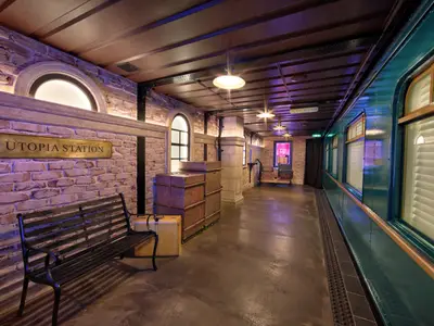 Thematisches Restaurant Utopia Station an Bord. Design als nostalgischer Bahnhof mit Ziegelwänden, Zugwagon und Schild 'Utopia Station'.