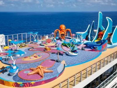 Buntes Oberdeck der Wonder of the Seas mit thematischem Mini-Golfplatz (Oktopus, Seestern) und einem Wasserspielbereich samt Rutschen, umgeben vom tiefblauen Meer.