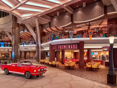 Die Royal Promenade der Wonder of the Seas: Rotes Oldtimer-Cabriolet vor dem Cafe Promenade. Im Hintergrund weitere Ebenen mit Bars, Geschäften und nautischen Dekorationen.