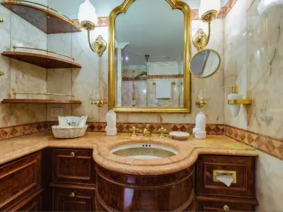 Luxuriöses Badezimmer mit Marmor, goldener Spiegelumrandung und Holzwaschtisch an Bord der Sea Cloud Ii.