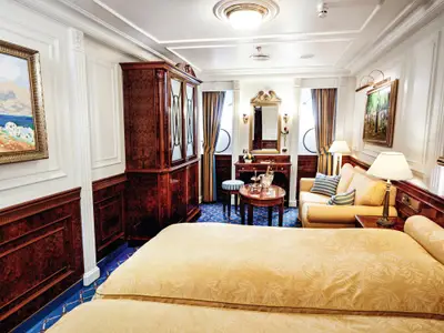 Elegante Kabine an Bord der Sea Cloud Ii mit großem Bett, edlem Holzschrank, Sofa und Schminktisch.