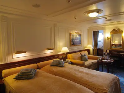 Blick in die gemütliche, klassisch gestaltete Außenkabine an Bord der Sea Cloud Ii mit zwei Betten und Sitzecke.