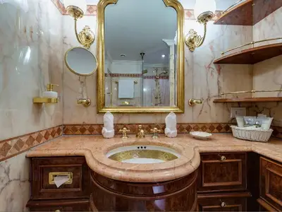 Marmorbadezimmer mit vergoldeten Armaturen, großem Spiegel und edlen Holzmöbeln an Bord der Sea Cloud Ii.