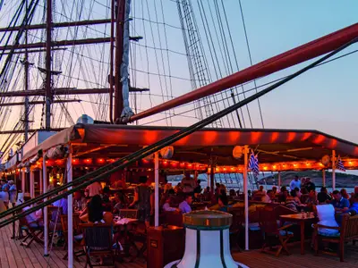 Gäste sitzen am Abend bei warmem Licht im überdachten Bar-Bereich an Deck der Sea Cloud II.
