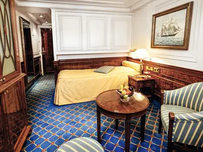 Blick in eine klassisch gestaltete Kabine an Bord der Sea Cloud Ii mit gelbem Bett, Holzvertäfelung und Obstschale.