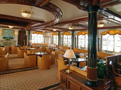 Die klassische Lounge an Bord der Sea Cloud II bietet gemütliche Ledersessel, große Fenster und ein edles Holzambiente.