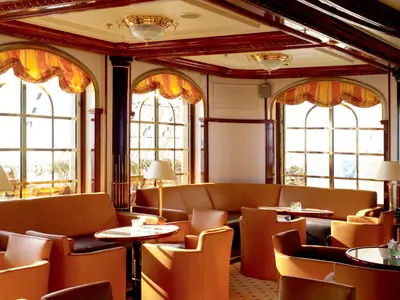 Die gemütliche Lounge an Bord der Sea Cloud Ii bietet edle Ledermöbel, Holzverkleidungen und große Bogenfenster mit Blick nach draußen.