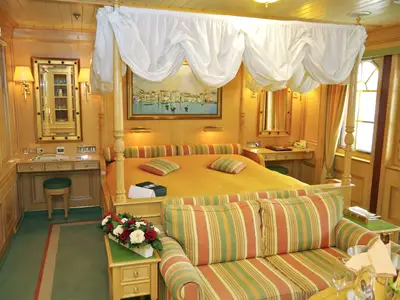 Elegante Suite an Bord der Sea Cloud Ii mit einem großen Himmelbett, gestreiftem Sofa und edler Holzvertäfelung.