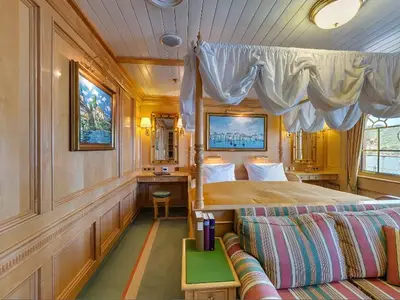 Elegante Owner Suite an Bord der Sea Cloud Ii mit edler Holzverkleidung, feinem Sofa und einem Baldachin-Himmelbett.