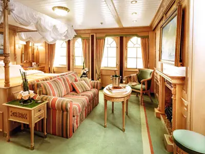 Elegante Owner Suite an Bord der Sea Cloud Ii mit rot-grün gestreiftem Sofa, Holzvertäfelung und Kamin.