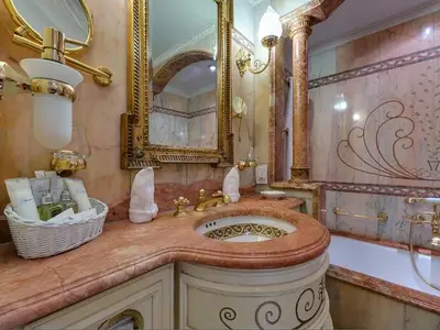 Elegantes Badezimmer mit rosa Marmor, goldenen Armaturen und Badewanne in einer Suite an Bord der Sea Cloud Ii.