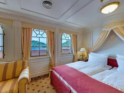 Luxuriöse Junior Suite an Bord der Sea Cloud Ii mit Doppelbett, Baldachin, Sofa und großen Fenstern zum Meer.