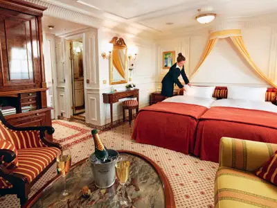 Eine Stewardess richtet das Bett in einer luxuriösen Suite mit Champagnerkühler an Bord der Sea Cloud Ii.