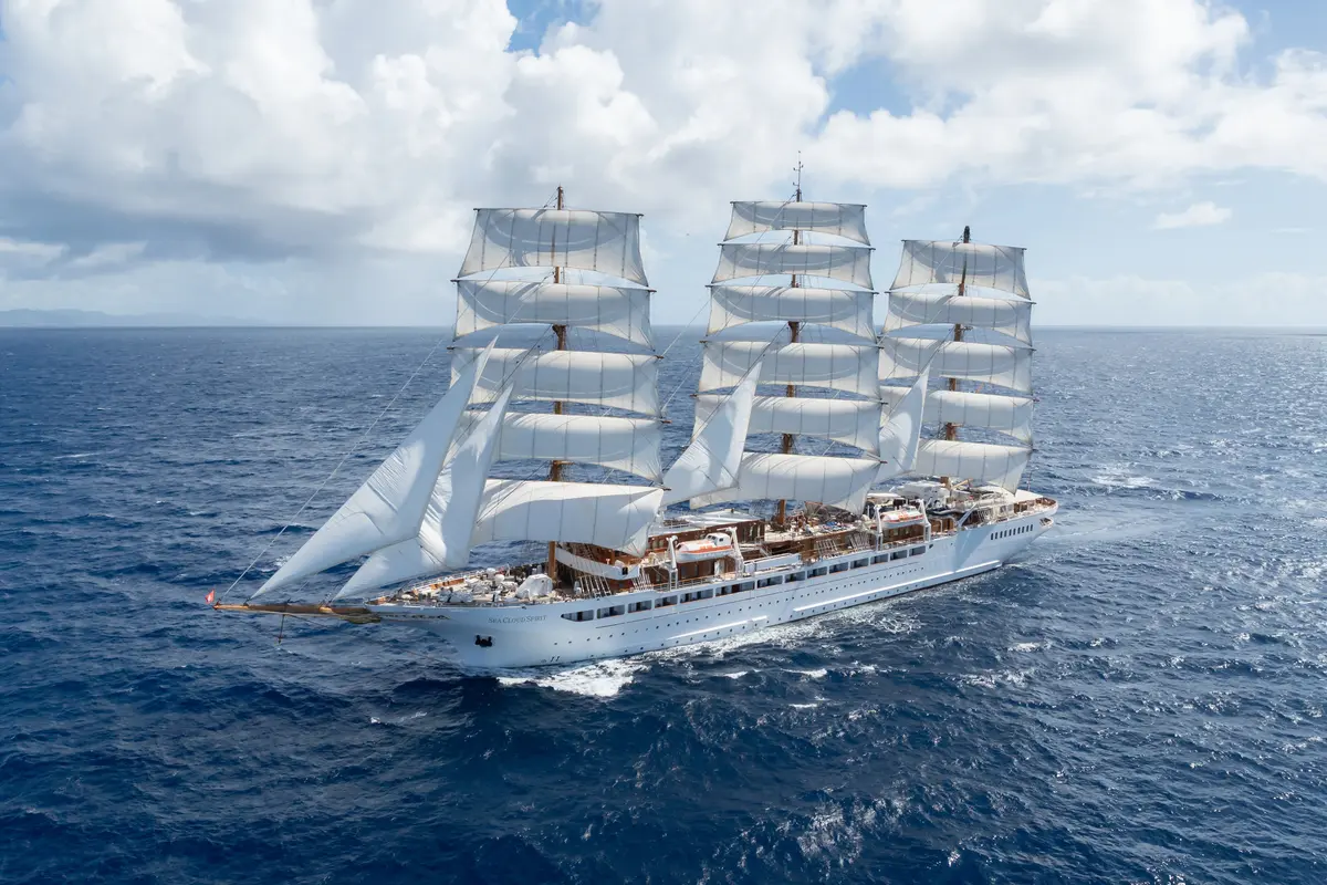 Die dreimastige Segelyacht Sea Cloud Spirit gleitet mit gesetzten weißen Segeln auf dem tiefblauen Ozean.