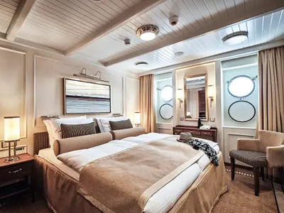 Elegante Außenkabine mit großem Doppelbett, Bullaugen und edlem Interieur an Bord der Sea Cloud Spirit.