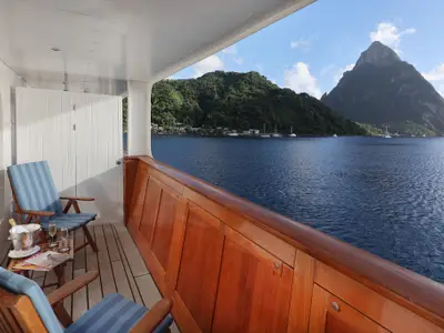 Balkon an Bord der Sea Cloud Spirit mit Holzreling, Liegestühlen, Champagner und Panoramablick auf St. Lucia.