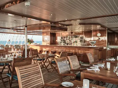 Blick auf die aus edlem Holz gestaltete Lido-Bar und Sitzecken an Bord der Sea Cloud Spirit mit Blick aufs Meer.