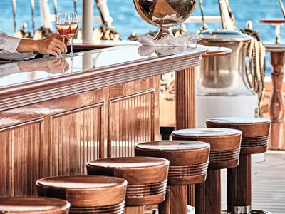 Glänzende Holzbar mit stilvollen Barhockern und Cocktails auf dem Außendeck der Sea Cloud Spirit.