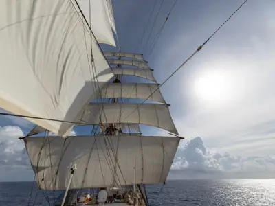 Blick von Deck der Sea Cloud Spirit nach oben in die weit aufgespannten weißen Segel und Masten bei Sonnenschein.