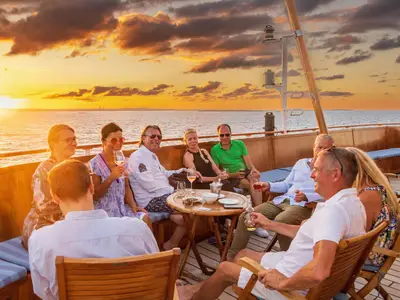 Eine Gruppe von Passagieren sitzt entspannt mit Drinks an Deck der Sea Cloud Spirit und schaut in den Sonnenuntergang.
