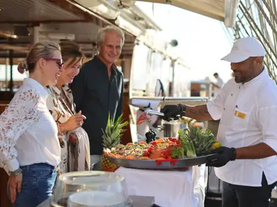Ein Koch präsentiert Gästen an Deck des Segelschiffs Sea Cloud Spirit eine große Platte mit frischen Meeresfrüchten.
