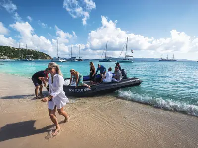 Gäste gehen von einem Tenderboot der Sea Cloud Spirit an einem tropischen Sandstrand an Land.