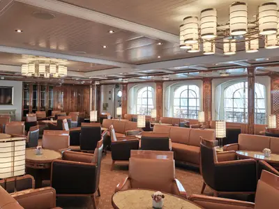 Die großzügige Lounge an Bord der Sea Cloud Spirit mit edlen Ledersesseln, Holzverkleidung und Kronleuchtern.