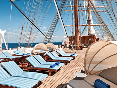 Gestreifte blaue Liegestühle und große Sonnensegel auf dem Holzdeck des Segelschiffs Sea Cloud Spirit.